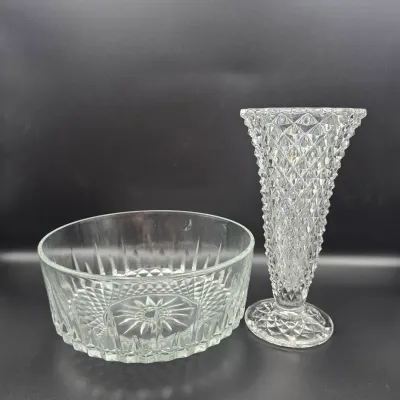 Two pieces of clear cut lead crystal glassware, including a low bowl with starburst bottom and a footed trumpet vase with a diamond pattern.