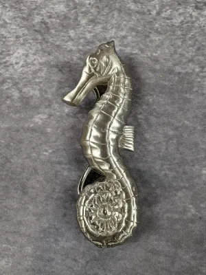 Vintage cast metal seahorse door knocker with a silver-tone finish, showing detailed scales and a curled tail.