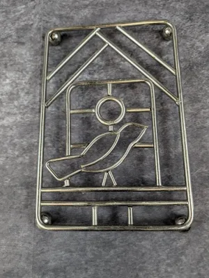Vintage metal wire trivet featuring a stylized bird in a cage design, supported by small ball feet.