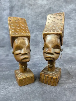 Pair of vintage hand-carved wooden African bust sculptures, featuring stylized heads with textured headdresses, neck rings, and metal...