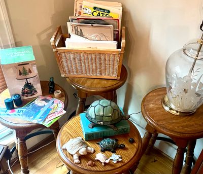 Assorted home decor items, including a stained glass turtle lamp, small turtle figurines, a wicker magazine rack, and a vintage etched...