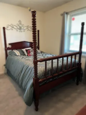 Traditional cherry wood four-poster bed frame featuring spool-turned posts and a matching spindle footboard.