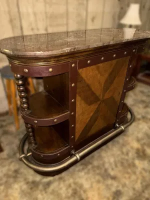 Traditional home bar unit featuring a polished stone top, parquetry wood paneling, brass-studded leather-look trim, open side shelving,...