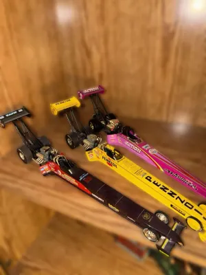 Three 1:24 scale die-cast top fuel dragster models, including a black Kalitta, a yellow Pennzoil, and a pink Shirley Muldowney...
