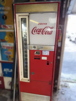 Vintage Cavalier CSS-64 Coca-Cola vending machine, featuring a light-up sign, vertical bottle viewing window, and 60-cent coin mechanism.