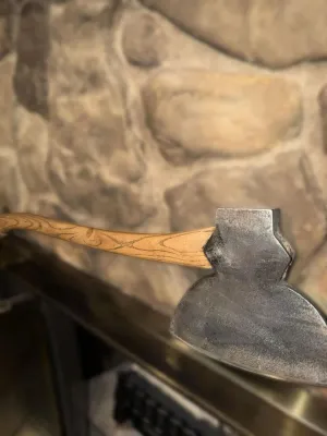 Vintage broad axe featuring a curved wooden handle with a prominent grain pattern and a hand-forged steel head.