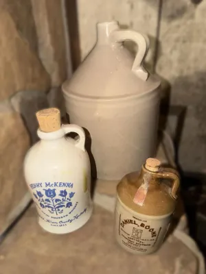 Collection of vintage ceramic whiskey jugs, including a Henry McKenna sour mash bourbon jug, a Daniel Boone Kentucky straight bourbon jug...