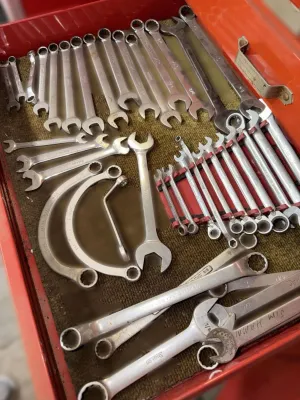 Assorted vintage combination, open-end, and specialty crescent wrenches organized inside a red metal toolbox drawer.