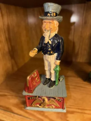 Vintage cast iron Uncle Sam mechanical bank, featuring a hand-painted finish with some wear consistent with age.