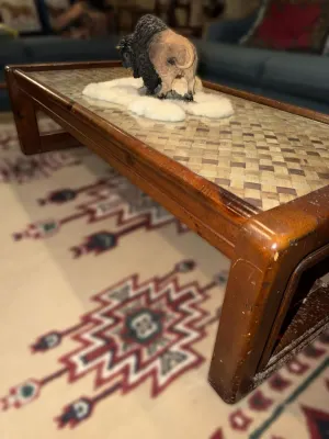 Mid-century modern style wooden coffee table featuring a woven rattan or bamboo top under glass, showing some wear on the wooden frame.