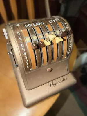 Vintage Paymaster Series 8000 check writer with a faux-woodgrain faceplate and manual sliding levers.