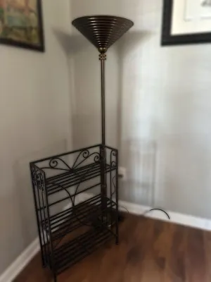 Modern bronze-finished torchiere floor lamp with a ribbed cone shade, paired with a three-tier black wrought iron baker's rack.