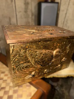Vintage brass or bronze-plated metal box featuring embossed duck and water motifs, showing some age-related patina and wear.