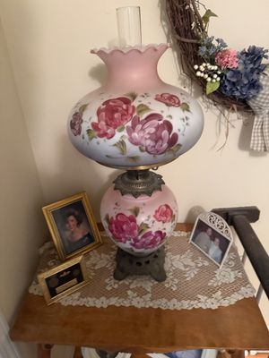 Vintage hurricane lamp featuring a pink frosted glass body and shade hand-painted with large rose motifs, mounted on an ornate metal base.