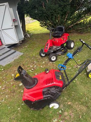Red Troy-Bilt riding lawn mower and a red gas-powered snowblower, both showing signs of outdoor use.