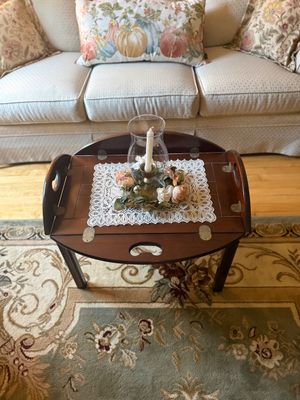 Traditional mahogany butler's tray coffee table with folding sides and brass hinges, styled with a lace doily and a glass hurricane...