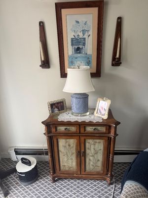 Traditional wooden accent cabinet featuring hand-painted floral panels, two drawers, and two doors, styled with a blue and white ceramic...