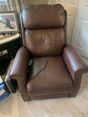 Brown leather power recliner with a wired remote control, showing minor wear on the armrests.