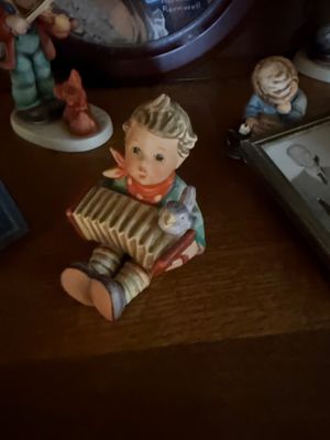 Vintage Goebel Hummel figurine depicting a young boy playing an accordion with a small bird perched on top.