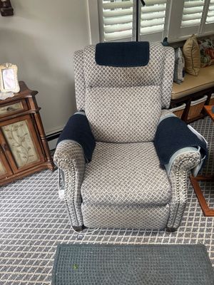 Upholstered power lift recliner featuring a diamond-patterned fabric, rolled arms with nailhead trim, and protective dark blue covers on...
