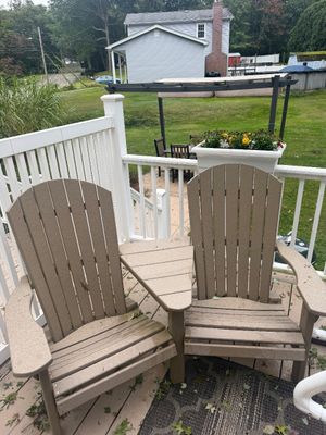 Double Adirondack chair set with a built-in connecting table, made of durable tan polywood material.