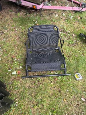Black mesh folding stadium seat with a metal frame, showing some wear from outdoor use.