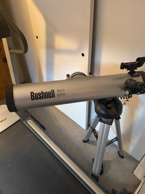 Bushnell NorthStar reflector telescope mounted on an adjustable aluminum tripod.