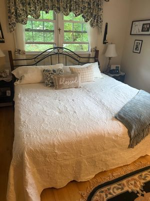 Traditional metal arch headboard and bed frame, shown with a white quilted coverlet, decorative throw pillows, and matching nightstands.