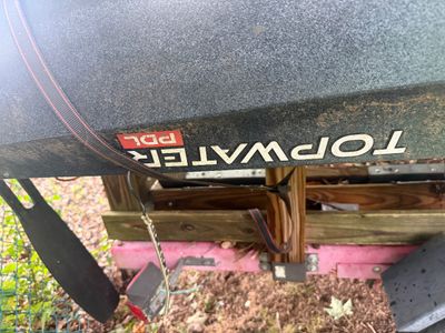 Old Town Topwater PDL kayak, shown upside down on a wooden rack with some dirt and wear from outdoor storage.