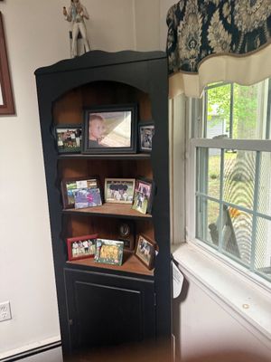 Vintage wooden corner hutch painted black, featuring three open shelves with scalloped trim and a lower cabinet door.