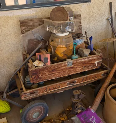 Vintage Aero Flyer wooden pull wagon loaded with various rustic items, including a wooden crate, rocks, a toy truck, and old tools.