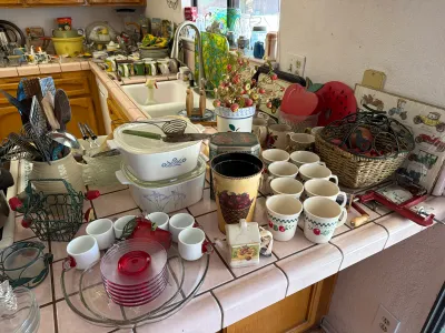 Assorted vintage kitchenware, including CorningWare casserole dishes, a collection of ceramic mugs, red glass plates, and various kitchen...