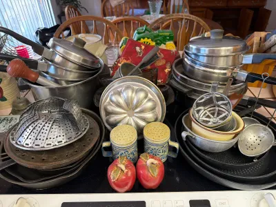 Assorted vintage kitchenware including stainless steel pots, a metal bundt pan, a steamer basket, and decorative salt and pepper shakers.
