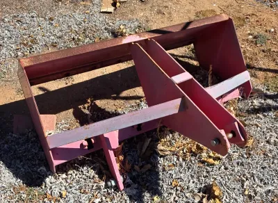 Pink tractor box blade attachment with a three-point hitch, showing some surface rust and wear from outdoor storage.