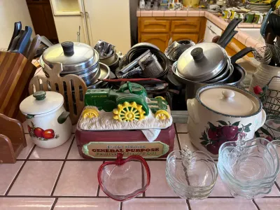 Assorted kitchenware including a John Deere ceramic tractor butter dish, apple-themed canisters, glass apple-shaped bowls, and various...