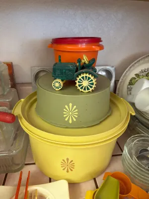 Vintage Tupperware nesting canisters in harvest colors, featuring the classic starburst pattern, topped with a small green and yellow toy...