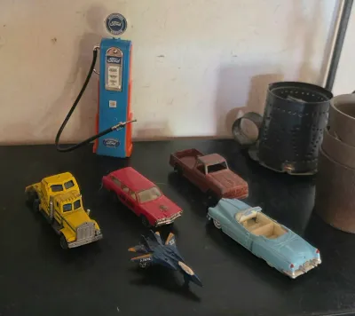 Collection of vintage die-cast toy vehicles, including a yellow semi-truck, a red fire chief car, a blue convertible, a brown pickup...