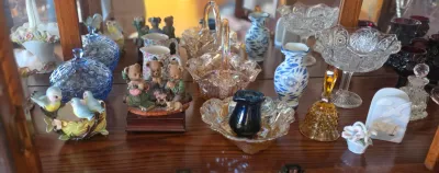 Collection of vintage glassware and figurines, including blue and amber carnival glass baskets, blue-and-white ceramic vases, and...