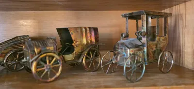 Collection of vintage miniature metal model cars, featuring a brass and copper finish with detailed spoked wheels.