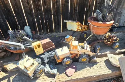 Collection of vintage Tonka pressed steel construction toys, including a dump truck, front loader, and excavator, showing significant...