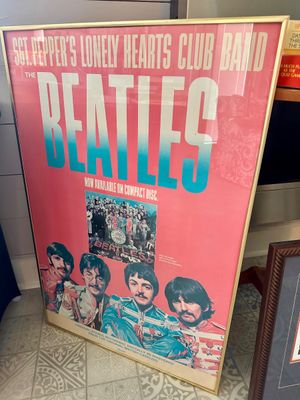 Framed promotional poster for The Beatles' "Sgt. Pepper's Lonely Hearts Club Band" compact disc release, featuring a...