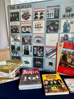 Collection of vintage Beatles memorabilia, including a framed album discography poster, "The Complete Beatles" book,...