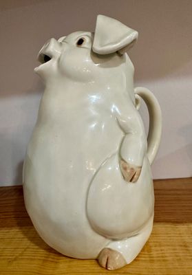 Vintage white ceramic pig pitcher, featuring a glossy glaze, molded details, and an open snout serving as the spout.