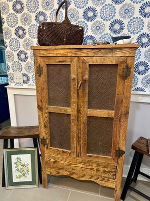 Rustic pine pie safe featuring punched tin door panels, a bottom drawer, and a woven basket resting on top.