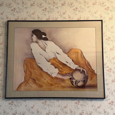 Framed Southwestern-style art print depicting an Indigenous woman with a decorated pottery bowl, rendered in earthy tones and housed in a...