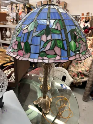 Sale Photo Thumbnail #37: Tiffany-style stained glass table lamp featuring a blue, green, and pink floral shade on an ornate brass base.