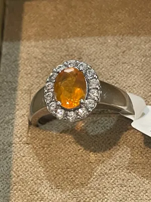 Sale Photo Thumbnail #69: Oval-cut orange citrine or sapphire ring set in white gold or platinum, featuring a halo of small round diamonds.