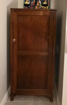 Antique oak sheet music or storage cabinet featuring a single paneled door, glass knob, and claw-and-ball feet.