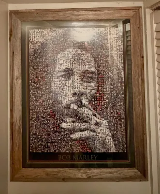 Framed Bob Marley photomosaic poster, featuring a portrait composed of smaller images, housed in a rustic wooden frame.