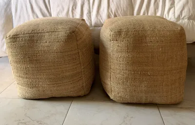 Pair of square woven jute pouf ottomans in a natural tan color, showing a textured, rustic style.